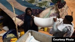 Un nouveau refugiée venu du Mali aident à transporter des sacs du riz, de l’huile et du sucre sur un véhicule dans le camp de M’Bera, dans la sud de la Mauritanie, 2 mars 2013.