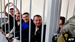 FILE - Ukrainian sailors sit inside a defendants' cage before a hearing at a court in Moscow, July 17, 2019.