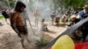 FILE - Neenan Simpson tends a smoldering fire that will be used for a smoking ceremony at an Indigenous Australians protest during Australia Day in Sydney, Friday, Jan. 26, 2024. 