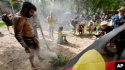 FILE - Neenan Simpson tends a smoldering fire that will be used for a smoking ceremony at an Indigenous Australians protest during Australia Day in Sydney, Friday, Jan. 26, 2024. 