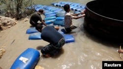 A group of men smuggle diesel fuel from Syria to Turkey hoping to sell it at a higher price, across the al-Assi River in Darkush town, Idlib, May 26, 2013. 