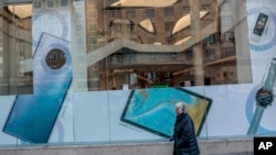 A woman and her dog walk past a Huawei shop in Madrid, Spain, Feb. 20, 2020.