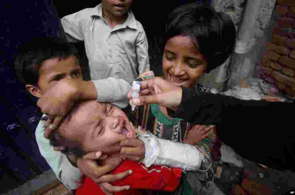 A health worker gives a polio vaccine to a child in Lahore, Pakistan.