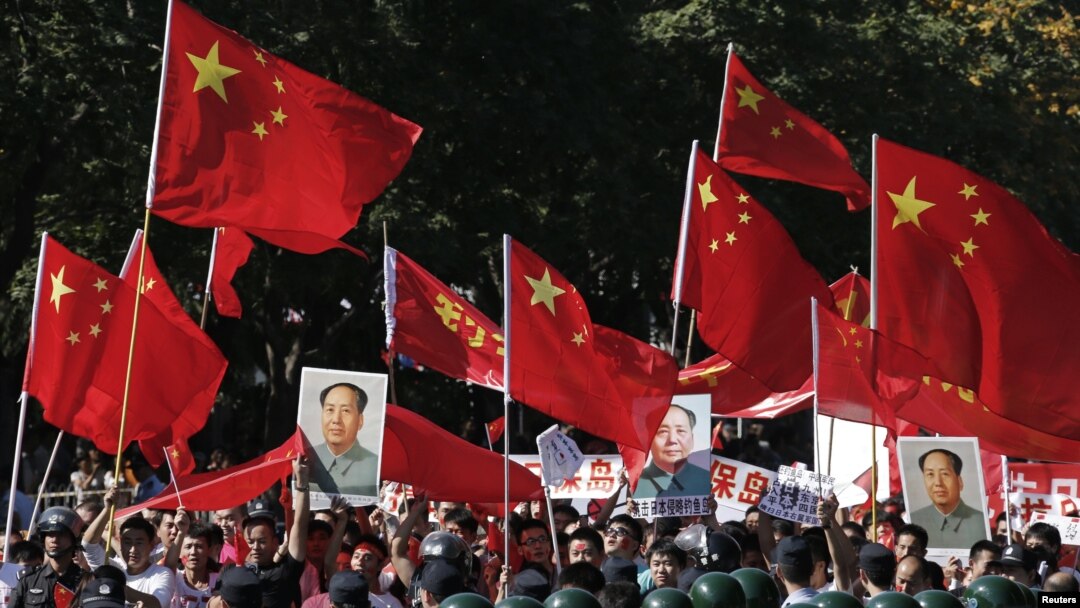 Demonstrators holding posters of China's late Chairman Mao Zedong, Chinese national flags and banners march past riot policemen during a protest on the 81st anniversary of Japan's invasion of China, outside the Japanese embassy in Beijing, September 18, 2