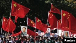 Demonstrators holding posters of China's late Chairman Mao Zedong, Chinese national flags and banners march past riot policemen during a protest on the 81st anniversary of Japan's invasion of China, outside the Japanese embassy in Beijing, September 18, 2