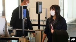 Japan's former Princess Mako, the elder daughter of Crown Prince Akishino, waits for her husband Kei Komuro, not in picture at a boarding gate to board an airplane to New York, Nov. 14, 2021, at Tokyo International Airport in Tokyo.