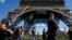 FILE - French CRS policemen patrol as tourists walk past in front of the Eiffel Tower in Paris, Aug. 20, 2016. 