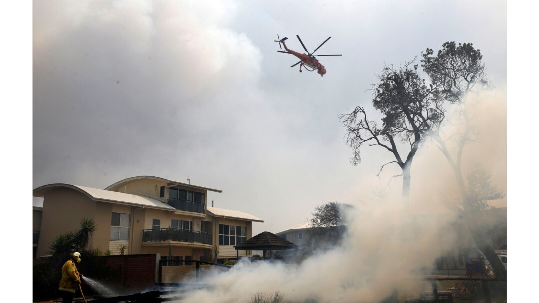 A fire bombing helicopter works to contain a bushfire along Old Bar road in Old Bar, New South Wales, Australia, Nov. 9, 2019. (AAP Image/Shane Chalker/via Reuters)