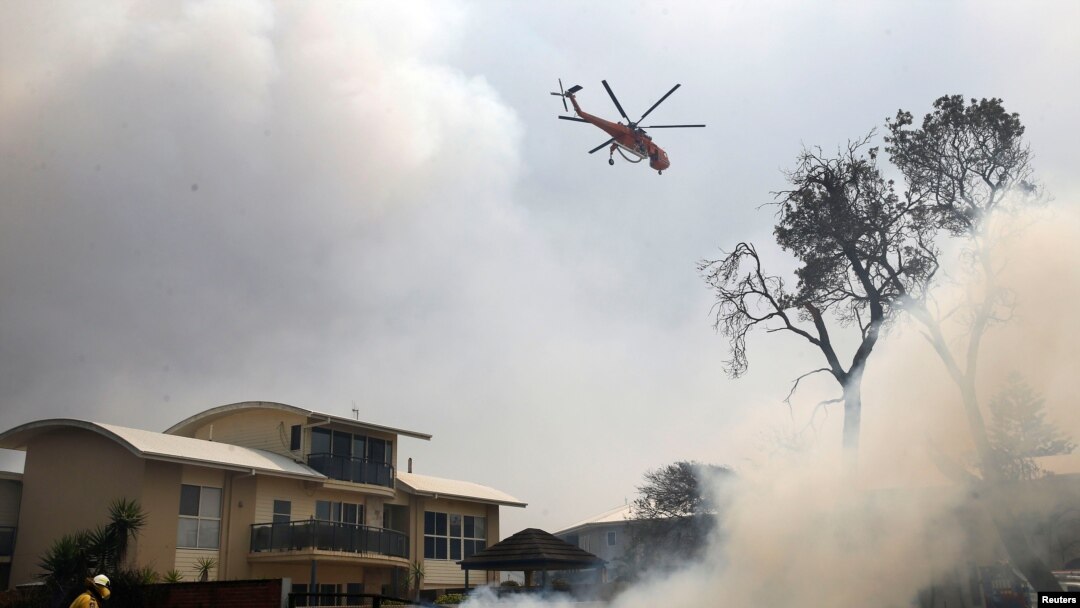 A fire-bombing helicopter works to contain a bushfire along Old Bar road in Old Bar, New South Wales, Australia, Nov. 9, 2019.