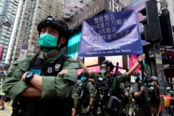 FILE - A police officer displays a warning banner on Oct. 1, 2020, China's National Day, in Causeway Bay, Hong Kong.