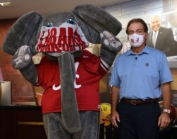 In this May 20, 2020 photo provided by the University of Alabama, football head coach Nick Saban and the school's elephant mascot, Big Al, wear masks on the university campus in Tuscaloosa, AL.