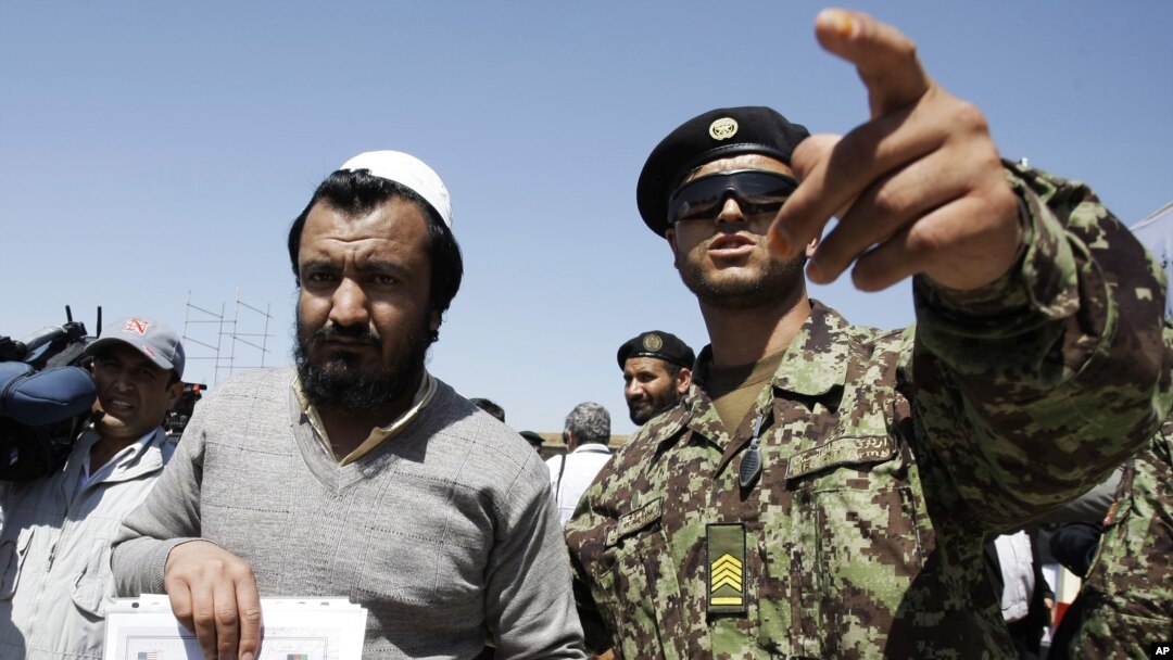Binh sĩ Afghanistan (phải) bên cạnh một tù nhân vừa được trả tự do từ nhà tù Bagram ở phía bắc thủ đô Kabul, ngày 10/9/2012