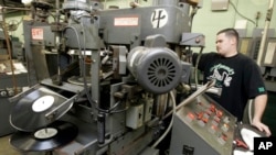 FILE - A man operates a vinyl record press at a company in Nashville, Tennessee. 