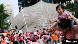 Seorang balita bermain bermain saat berlangsung festival tahunan Pink Dot yang diadakan di Hong Lim Park, Singapura, 28 Juni 2014. Pink Dot diadakan untuk mengkampanyekan penerimaan komunitas LGBT (lesbian, gay, biseksual dan transgender) di Singapura.