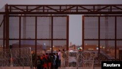 Migrantes se reúnen cerca del muro fronterizo después de cruzar el río Bravo con la intención de entregarse a los agentes de la Patrulla Fronteriza de Estados Unidos para solicitar asilo, visto desde Ciudad Juárez, México, el 22 de octubre de 2023.