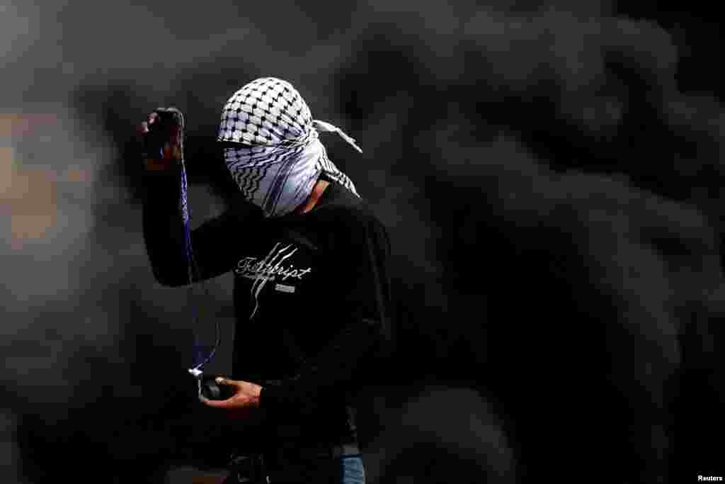 A Palestinian demonstrator uses a sling to hurl stones at Israeli troops during a protest against Jewish settlements, in Kafr Qaddum town in the Israeli-occupied West Bank.