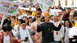 Indonesian President Joko Widodo, center right, walks and his running mate Ma'ruf Amin during a ceremony marking the kick off of the campaign period for next year's election in Jakarta, Sept. 23, 2018. Indonesia is set to hold its presidential and parliamentary election in April 2019.