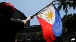 Seseorang mengibarkan bendera Filipina di Manila, Filipina pada Jumat, 21 Juni 2019. Menteri Pertahanan Filipina Gilberto Teodoro pada Senin (5/2) bertekad akan “benar-benar menegakkan” kedaulatan negara tersebut. (Foto: AP)