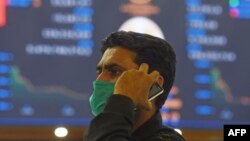 Seorang pialang mengenakan masker di tengah kekhawatiran wabah virus corona (COVID-19) di Bursa Saham Pakistan (PSX) di Karachi, 16 Maret 2020. (Foto: AFP)