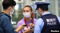 Belarusian athlete Krystsina Tsimanouskaya talks with a police officer at Haneda international airport in Tokyo, Japan August 1, 2021. REUTERS/Issei Kato