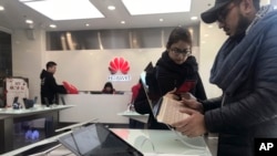 Foreigners look at a Huawei computer at a Huawei store in Beijing, China, Thursday, Dec. 6, 2018. Canadian authorities said Wednesday that they have arrested the chief financial officer of China's Huawei Technologies for possible extradition to the United States.