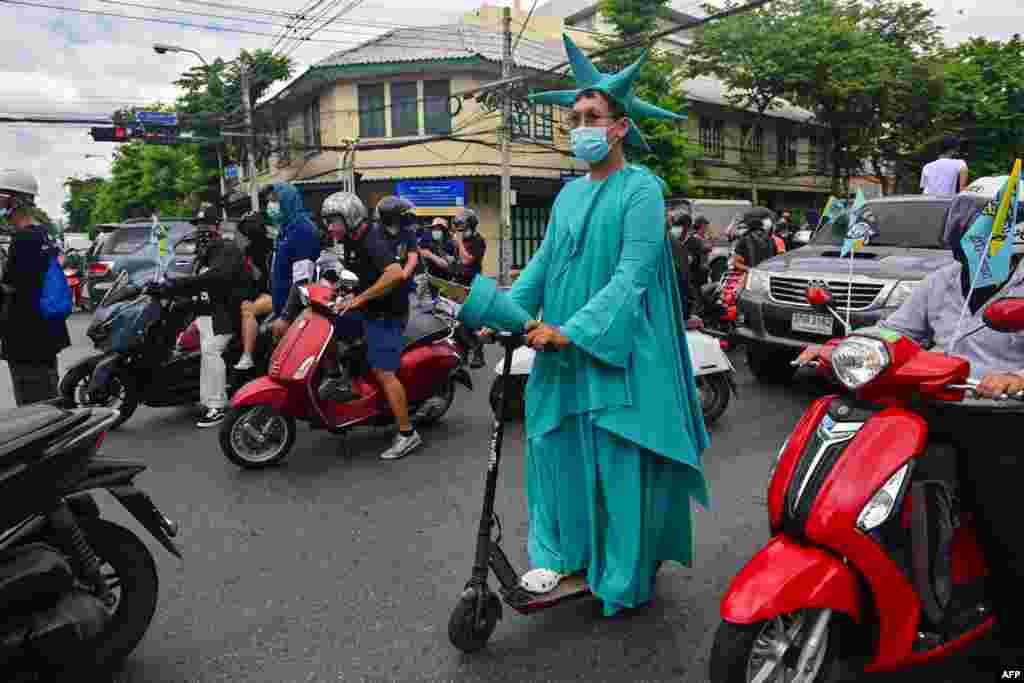 A pro-democracy protester dressed up as the Statue of Liberty rides an electric scooter during an anti-government demonstration as they commemorate the anniversary of the 1932 Siamese Revolution in Bangkok, Thailand.