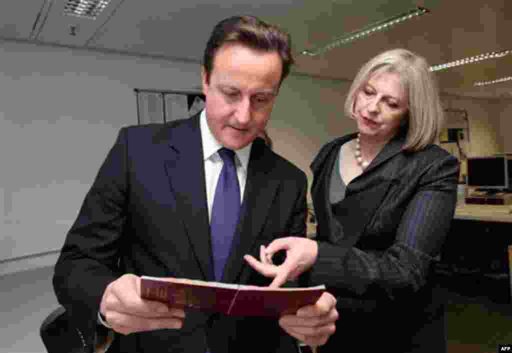 British Prime Minister David Cameron and Home Secretary Theresa May, right, visit the UK Border Agency staff at Terminal 5 of Heathrow Airport, London where they were shown differences between fake and real passports Tuesday Nov. 23, 2010. Britain's Home 