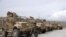 An Afghan army soldier walks past Mine Resistant Ambush Protected vehicles, MRAP, that were left after the American military left Bagram air base, in Parwan province north of Kabul, Afghanistan, July 5, 2021.