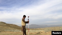 FILE - A man works at a road construction site, which is being built by a Chinese company, in Khogyani district of Nangarhar province, Nov. 19, 2015. 