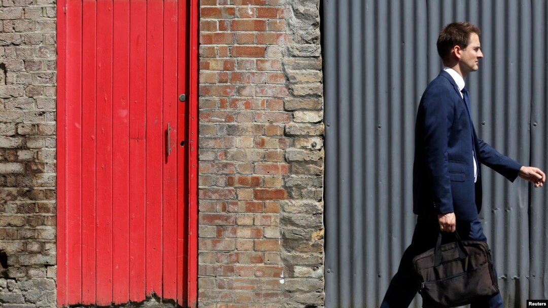 FILE - A man passes a red door and corrugated iron in central London, July 2, 2014. Asylum seekers in the northern English town of Middlesbrough are suffering abuse because they have been housed in properties that almost all have red front doors, making them easy targets for racists.