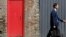 FILE - A man passes a red door and corrugated iron in central London, July 2, 2014. Asylum seekers in the northern English town of Middlesbrough are suffering abuse because they have been housed in properties that almost all have red front doors, making them easy targets for racists.