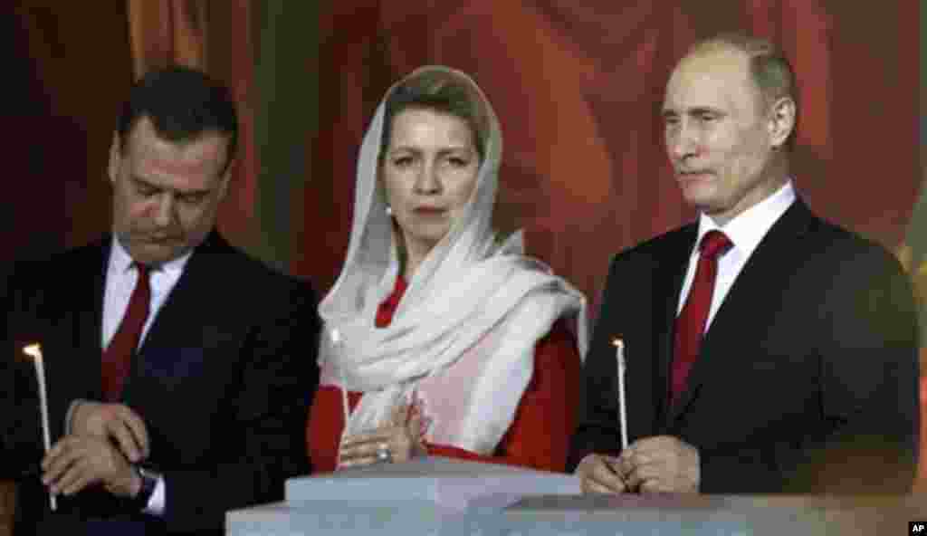 Russian President Vladimir Putin, right, Prime Minister Dmitry Medvedev, left, and his wife Svetlana attend the Easter service in Christ the Savior Cathedral in Moscow, Russia, early Sunday, April 20, 2014. This year Easter is celebrated on the same day f