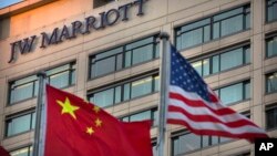 FILE - Chinese and American flags fly outside of a JW Marriott hotel in Beijing, Jan. 11, 2018. 