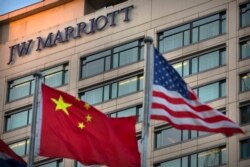 FILE - Chinese and American flags fly outside a JW Marriott hotel in Beijing, Jan. 11, 2018.