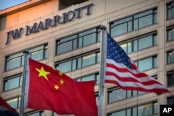 FILE - Chinese and American flags fly outside a JW Marriott hotel in Beijing, Jan. 11, 2018.