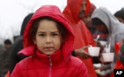 A refugee girl walks in the rain at an improvised camp on the border line between Macedonia and Serbia near northern Macedonian village of Tabanovce, March 10, 2016.