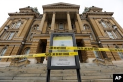 Police tape is wrapped around a sign in front of a closed entrance at the Statehouse in Des Moines, Iowa, March 16, 2020. Iowa leaders are suspending the legislative session for at least 30 days because of the coronavirus.