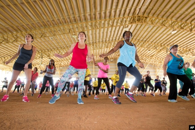 FILE - Fitness enthusiasts run through dance exercises as they work out at Tropical Park in Miami, Florida.