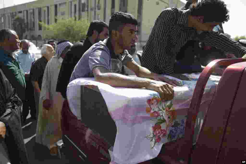 Relatives of a man who was killed in a car bomb attack grieve over his casket during his funeral in Baghdad, August 15, 2013. 