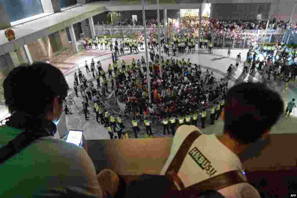 People look on from a vantage point as pro-democracy demonstrators are seen surrounded by police after storming into a courtyard outside Hong Kong's legislative headquarters. Students have been protesting for the last five days against Beijing's refusal last month to grant the former British colony full democracy. 