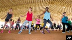 FILE - Fitness enthusiasts run through dance exercises as they work out at Tropical Park in Miami, Florida, July 25, 2015.