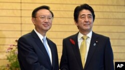 中国国务委员杨洁篪（左）访问日本与日本首相安倍晋三握手。