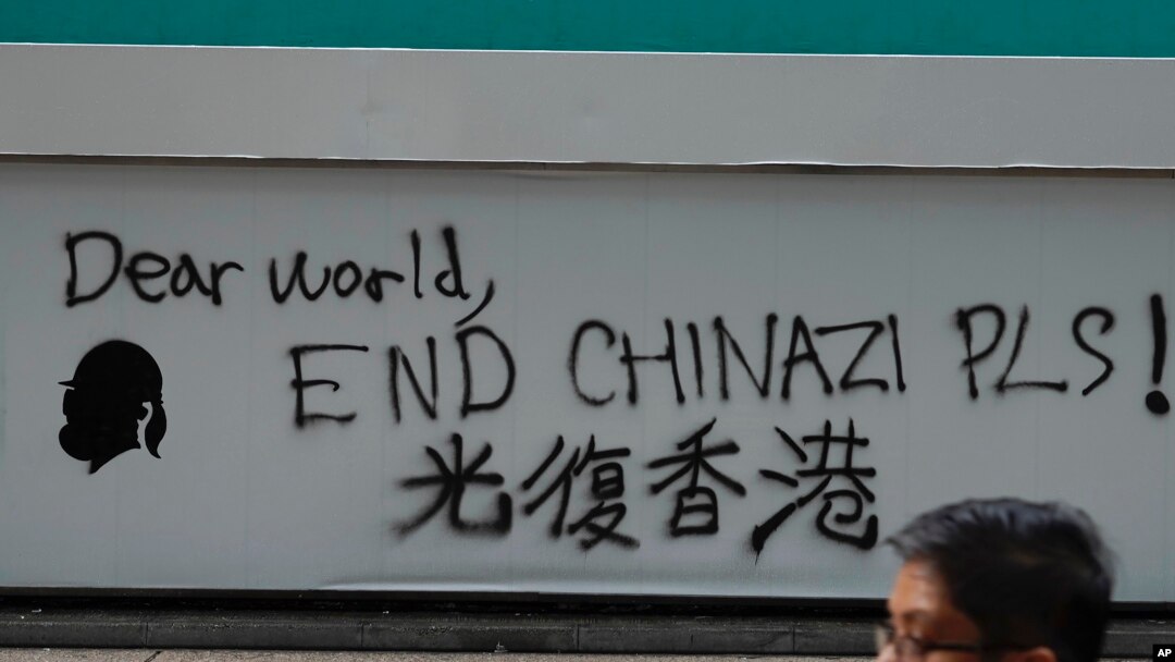 A man walks past a wall with the words ‘Liberate Hong Kong- Dear World End Chinazi Please’ in Hong Kong, Monday, Oct. 7, 2019.