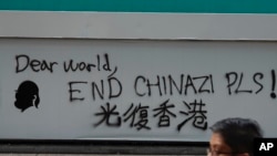 A man walks past a wall with the words ‘Liberate Hong Kong- Dear World End Chinazi Please’ in Hong Kong, Monday, Oct. 7, 2019.