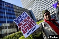 FILE PHOTO: A woman holds a placard as Haitian immigrants and supporters rally to reject DHS Decision to terminate TPS for Haitians, at the Manhattan borough in New York, Nov. 21, 2017.