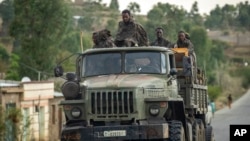 FILE - Ethiopian government soldiers ride in the back of a truck on a road leading to Abi Adi, in the Tigray region of northern Ethiopia, May 11, 2021.