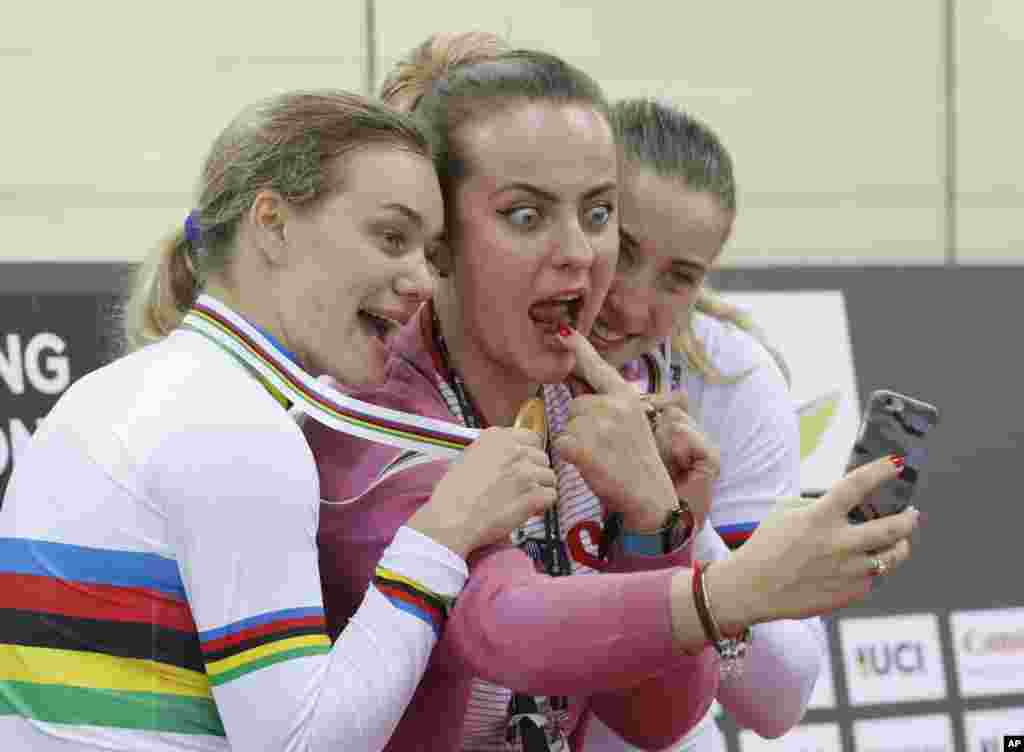 Russia's Anastasiia Voinova, left, and Daria Shmeleva, right, pose for a selfie with an unidentified woman after winning the gold medal in the Women's Team Sprint at the World Track Cycling championships in Hong Kong.
