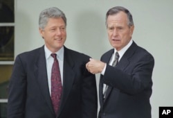 U.S. President George H. Bush gestures towards President-elect Bill Clinton at the White House, Wednesday, Nov. 18, 1992 in Washington. The President-elect made his first visit to the nation's capital since his election and met with the President as part