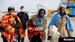 FILE - Migrants disembarks from a coast guard vessel in the Sicilian harbour of Augusta, Italy, Feb. 25, 2017.