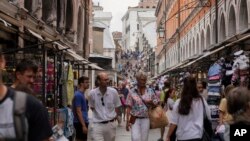 FILE -Tourists walk in a crowded street in Venice, Italy, on Sept. 13, 2023. Venice on Dec. 30 announced new limits on the size of tourist groups in a measure aimed at reducing the pressure of mass tourism on the famed canal city.